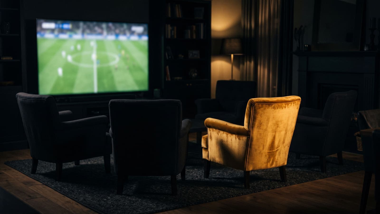 Five armchairs facing a football match on screen, one of them gold — a private prediction league where one friend tops the table